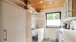 A compact kitchen with white cabinetry, a built-in oven, and a window providing natural light. - Vacation apartment - Klenk - 1 (Gruibingen)