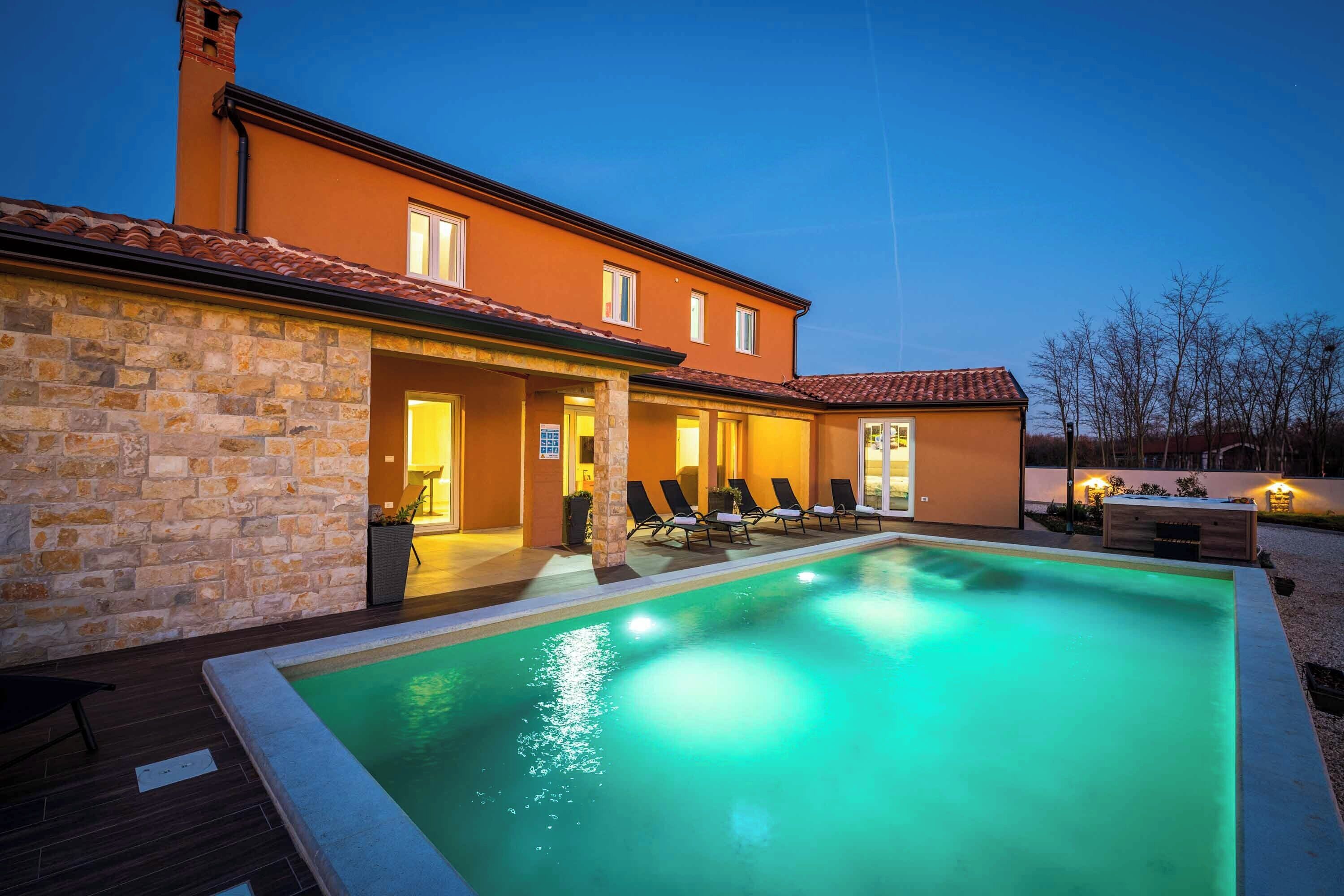 A modern house with a swimming pool, stone walls, and a tiled roof.