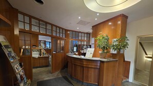 Un área de recepción con paneles de madera, una mesa con una planta y suelo de baldosas.