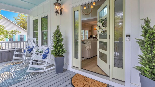 Eine Veranda mit Schaukelstühlen, einem Blumentopf und einer Tür zu einer Küche.