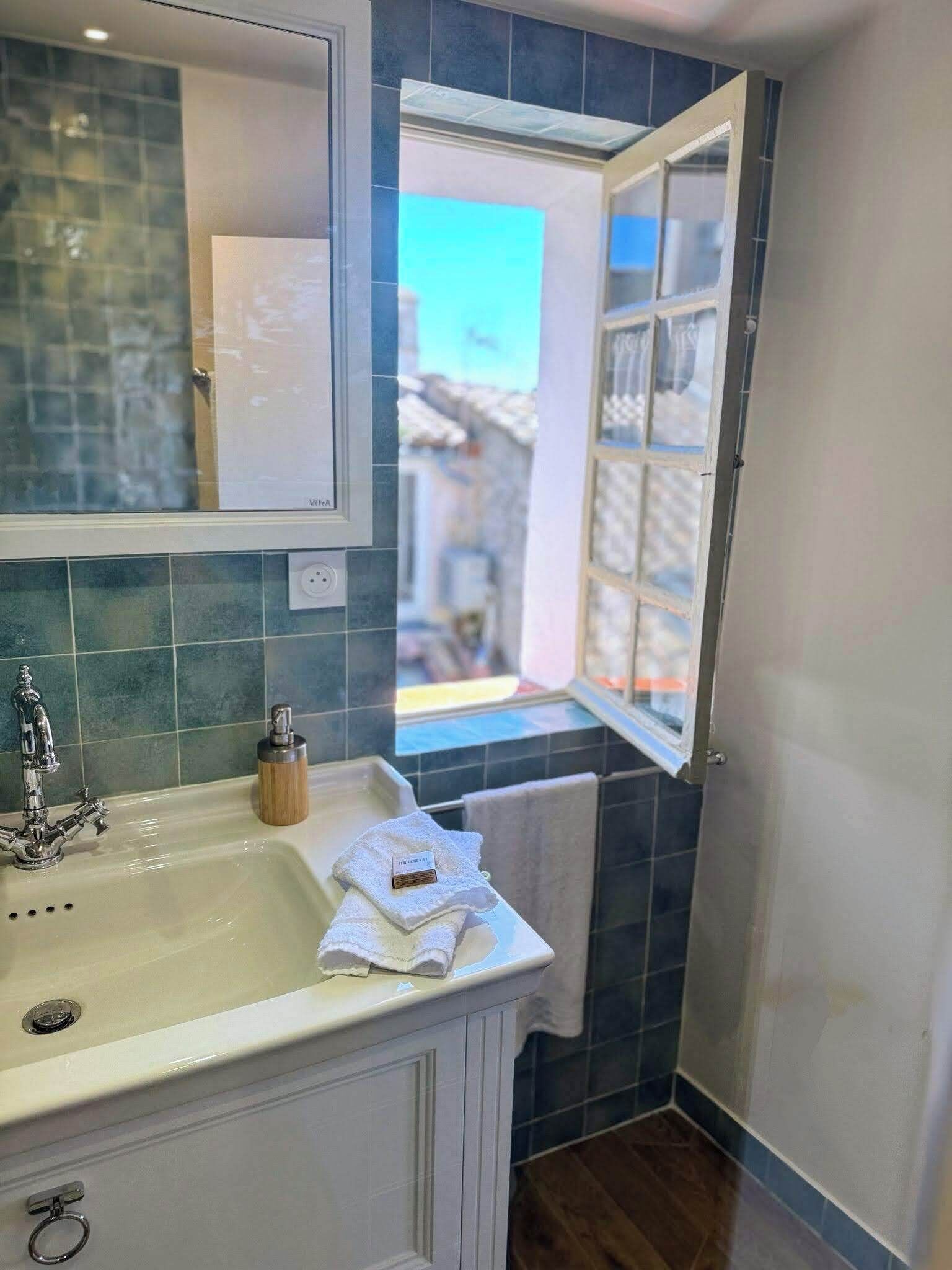 A bathroom with a sink, mirror, and window.