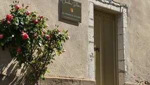 Un edificio con un cartel que dice "Chambers of the Dead", una pared de piedra, una puerta y plantas en macetas.