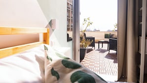 A bedroom with a bed, a window, and a view of an outdoor patio with a table and chairs. - P.C. BOUTIQUE H. CASTEL NUOVO by ClaPa Group Dislocated Hospitality (Naples)