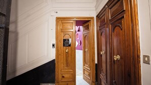 A hallway with a wooden door, a reception desk, and a purple wall. - P.C. BOUTIQUE H. CASTEL NUOVO by ClaPa Group Dislocated Hospitality (Naples)