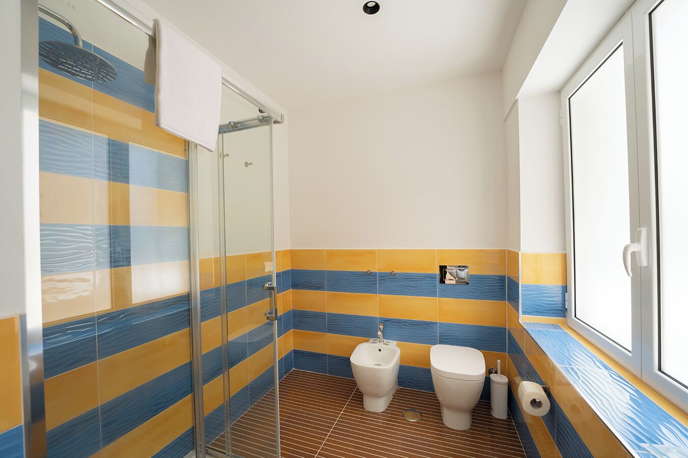 Et badeværelse med en brusekabine i glas, toilet og bidet.