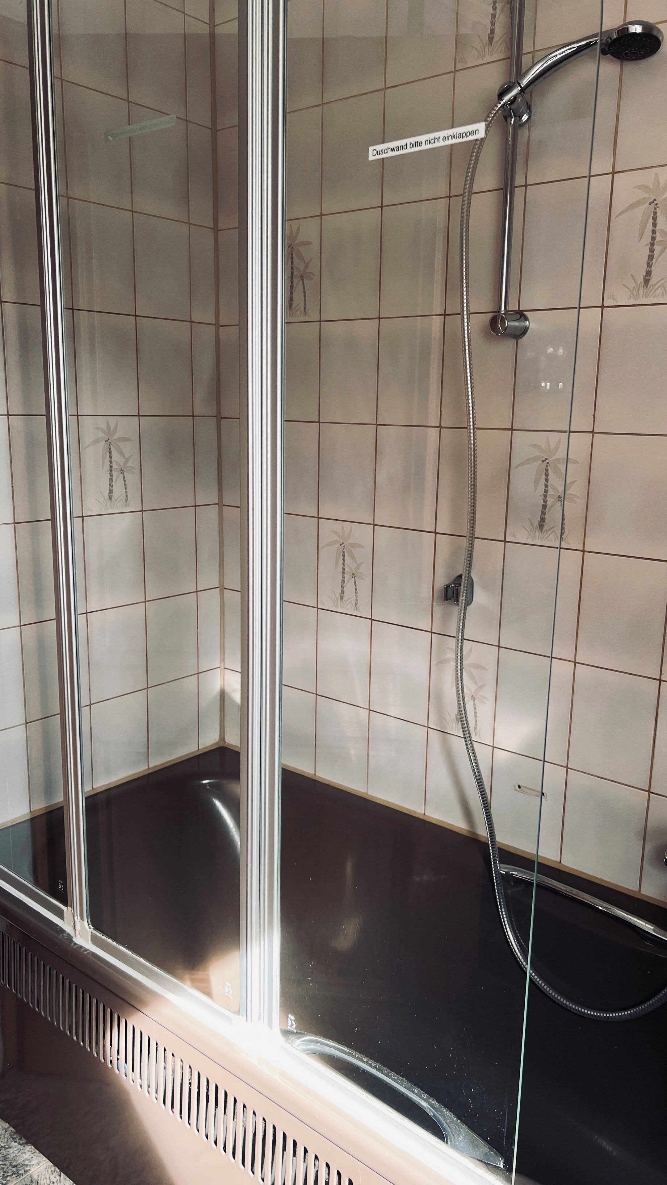 A shower area with a glass door, tiled walls, and a showerhead.