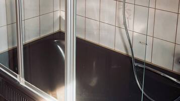 A shower area with a glass door, tiled walls, and a showerhead.