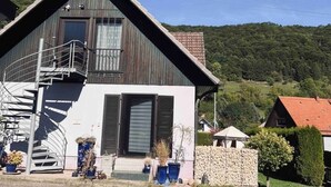 Une maison moderne à deux étages, dotée d’un toit en métal, d’un escalier en colimaçon et d’un mur en pierre à l’avant.