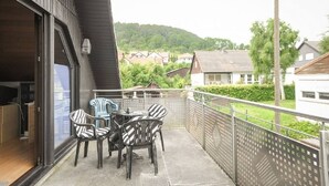 Un balcon avec une table et des chaises, une vue sur des maisons et une clôture.