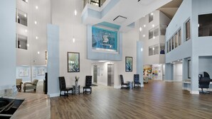 A spacious lobby with a high ceiling, wooden flooring, and a central reception area.