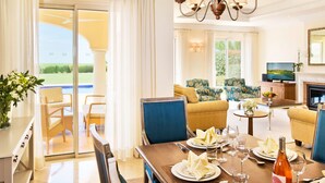Une chambre d  ’hôtel comprenant un coin repas, un ensemble de canapés, une télévision et une cheminée.
