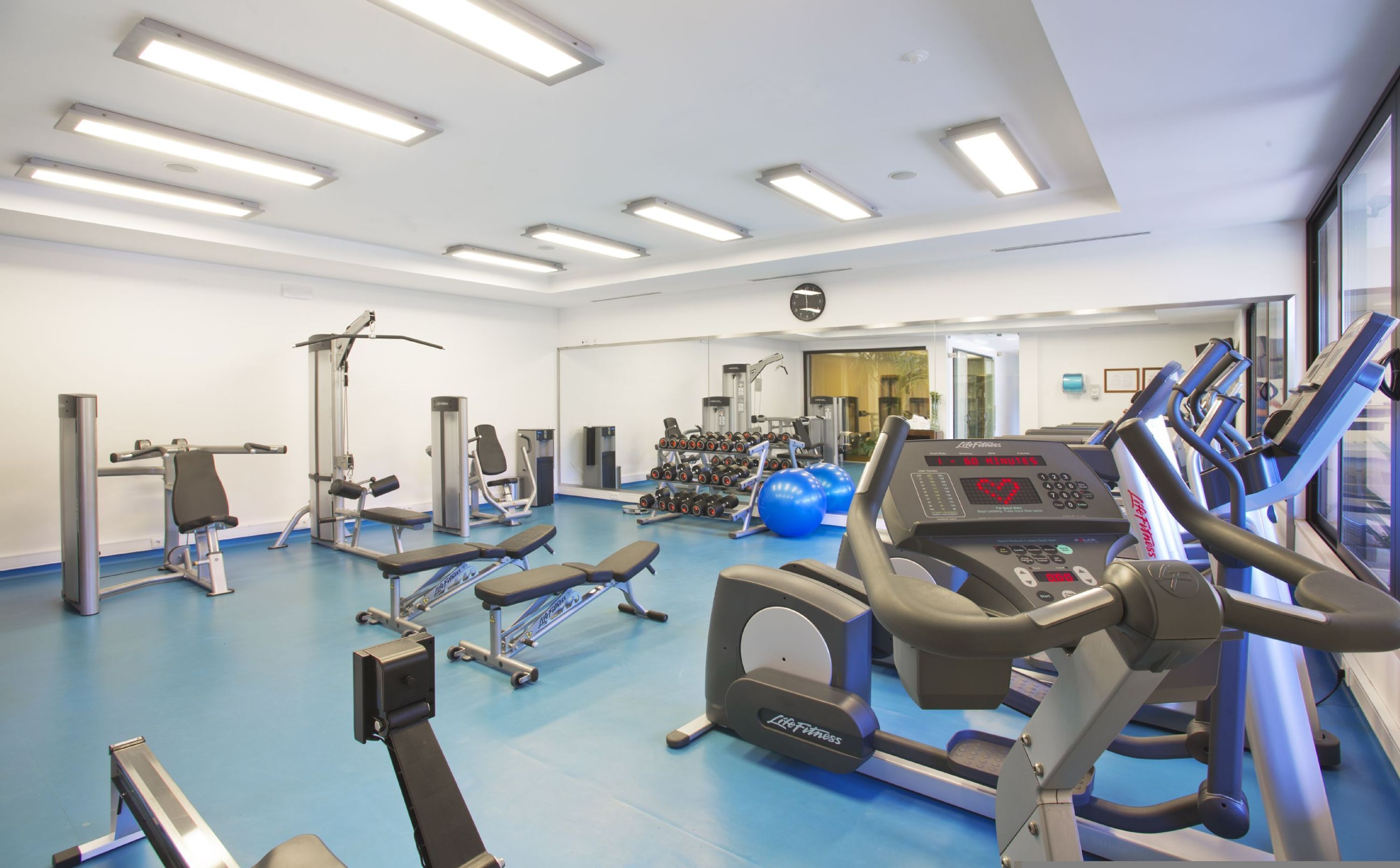Un gimnasio con cintas de correr, máquinas de pesas y pelotas de ejercicio.
