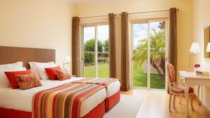 Une chambre d’hôtel avec un grand lit, un bureau et une vue sur un jardin.