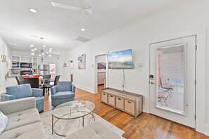 Ein modernes Wohnzimmer mit einer Couch, Sesseln, einem Couchtisch und einem Fernseher.