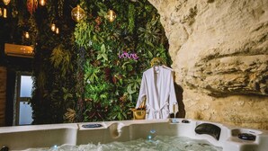 A spa area with a hot tub, surrounded by lush greenery and a neon 'love' sign. - La Grotte Fleurie - 5-star rating (Mussidan)