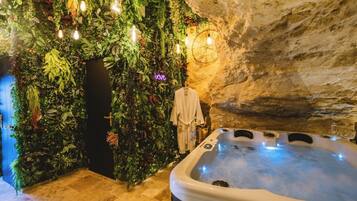 Un espace de bien-être comprenant un jacuzzi, un mur recouvert de verdure et un mur en pierre rustique.