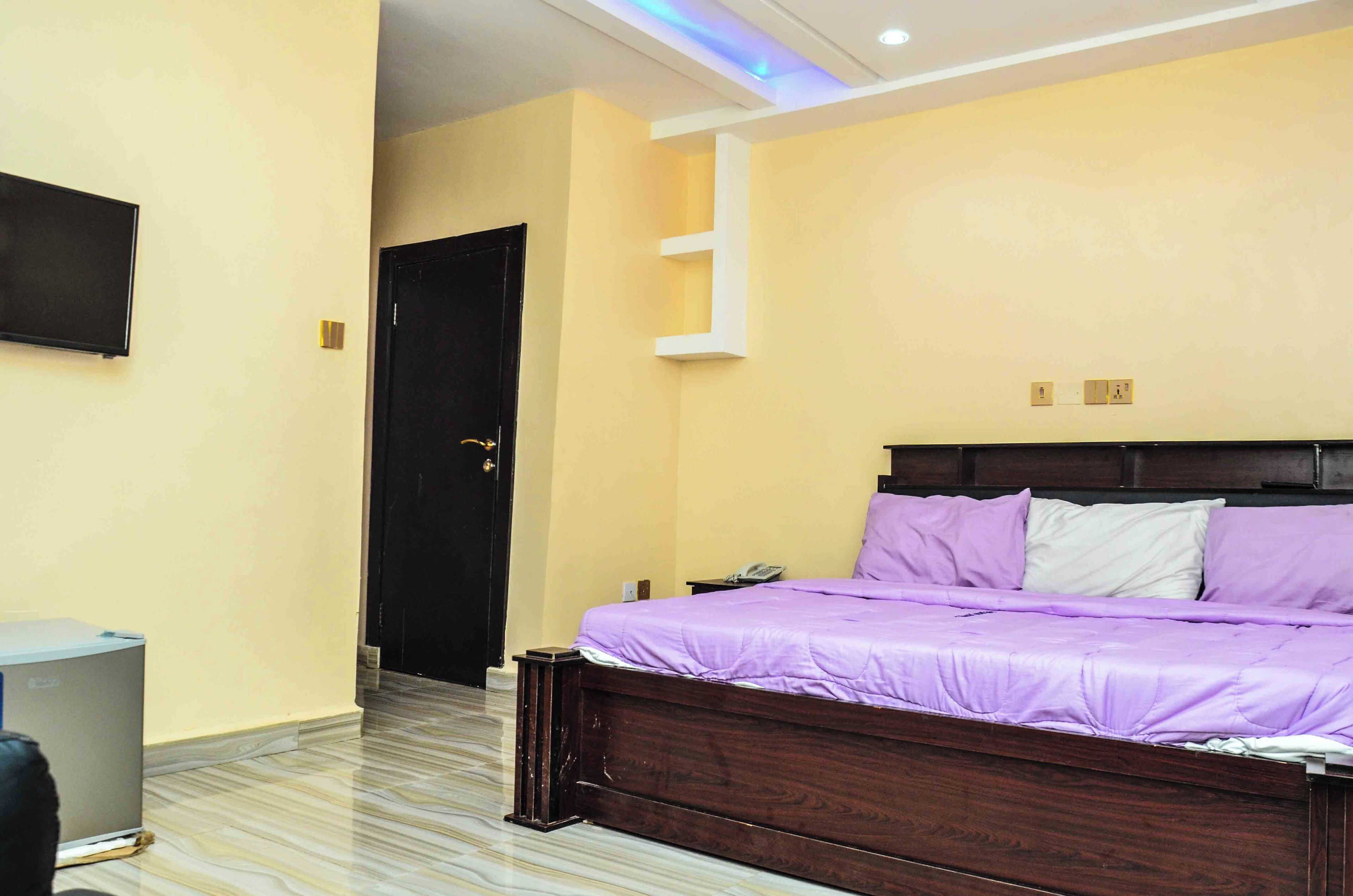 A bedroom with a bed, a TV, and a door.