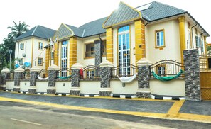 A multi-story residential building with a symmetrical facade, featuring a central entrance flanked by two wings. - Omenma Hotels & Conference Centre (Umuezee Ezuhu Nguru)