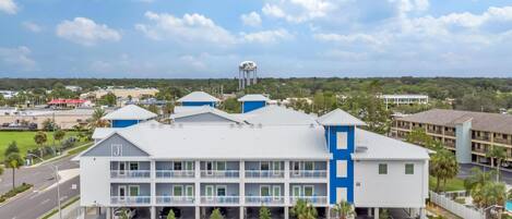 A multi-story hotel with a parking lot in front, a water tower in the background, and a clear sky.