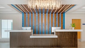 A reception desk with a wooden finish and a blue accent wall. - The J Hotel Dunedin near Honeymoon Island State Park, an Ascend Collection Hotel (Dunedin)