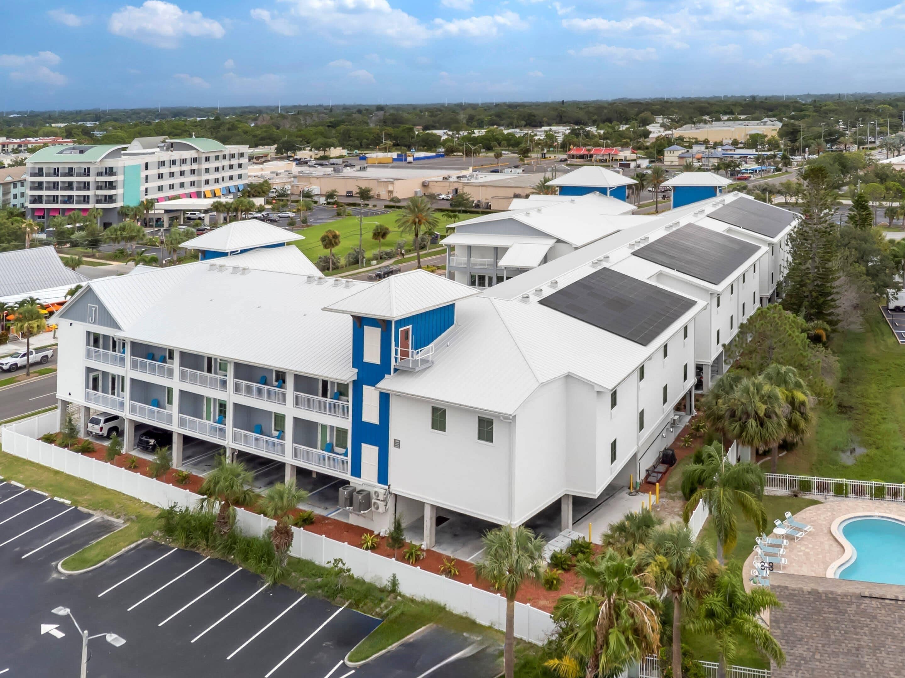 A multi-story hotel with a parking lot, a swimming pool, and a view of the surrounding area.