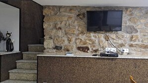 A stone wall with a flat-screen TV mounted above a counter. - Village of Moura Morta (Castro Daire)