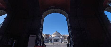 An open archway leading to a building with a dome, under a clear blue sky.