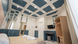 A modern hotel room with a large bed, a wooden wardrobe, a small table, and a TV mounted on the wall. - MEDINA ART & LIFESTYLE NAPOLI CENTRO by ClaPa Group Dislocated Hospitality (Naples)