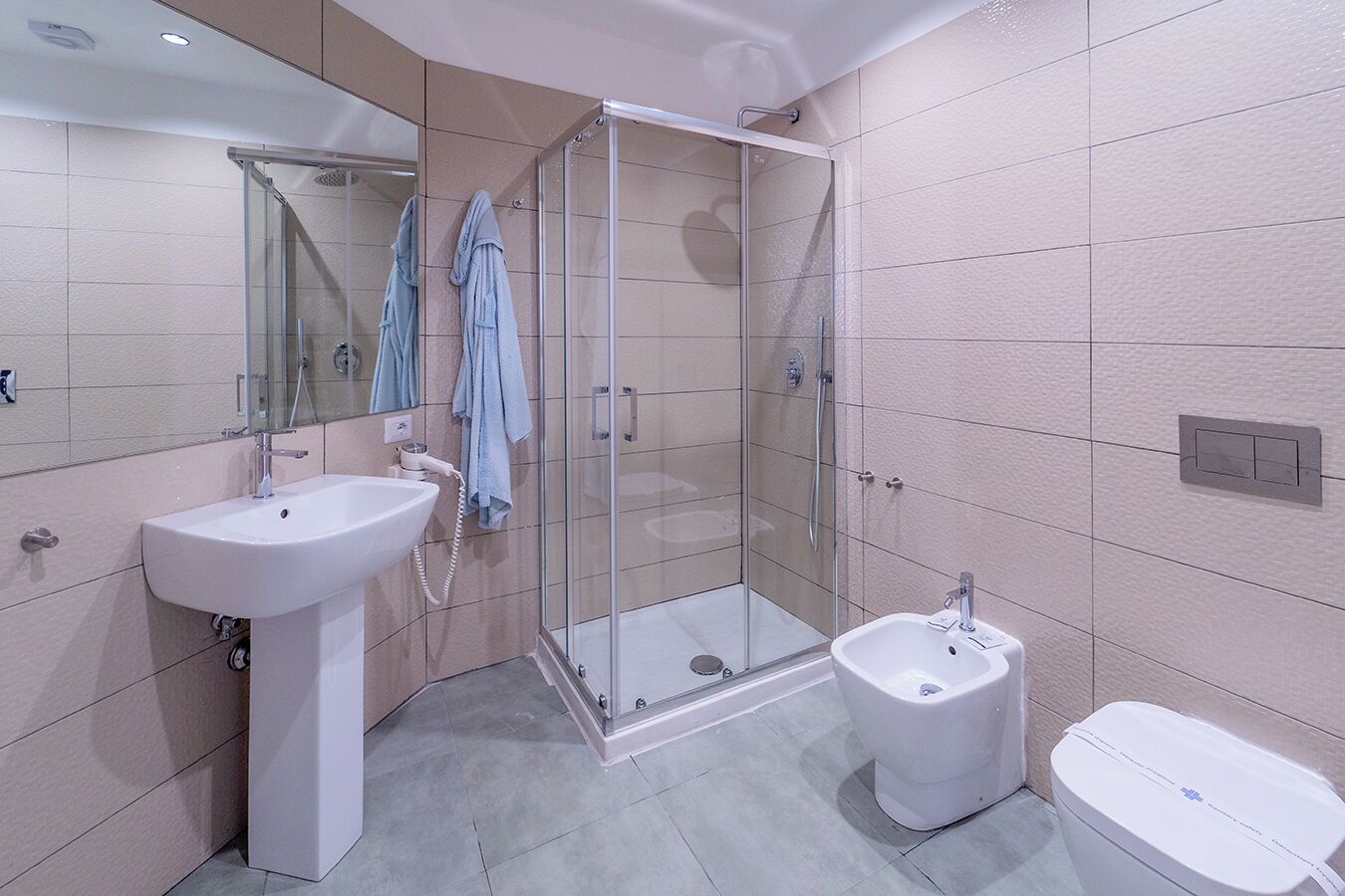 Une salle de bain moderne avec une douche à parois de verre, un lavabo sur colonne et des toilettes.