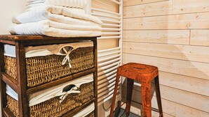Une pièce avec un mur en bois, un meuble de rangement en osier contenant des serviettes et un tableau encadré accroché au mur.