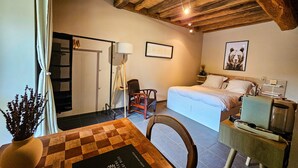 Une chambre confortable avec un plafond en bois, un lit recouvert de draps blancs, une table de chevet avec une lampe et un tableau encadré au mur.