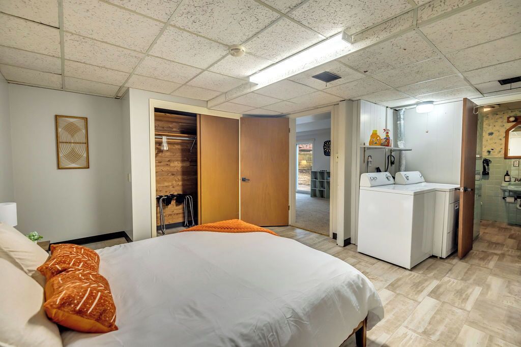 Une chambre d’hôtel avec un lit, une armoire, un bureau et une salle de bain, visibles à travers une porte ouverte.