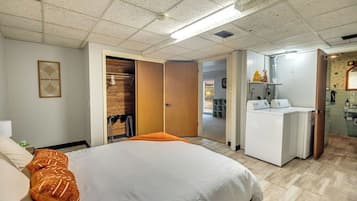 Une chambre d’hôtel avec un lit, une armoire, un bureau et une salle de bain, visibles à travers une porte ouverte.