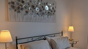 Een slaapkamer met een bed, twee bedlampen en een kunstwerk boven het bed.
