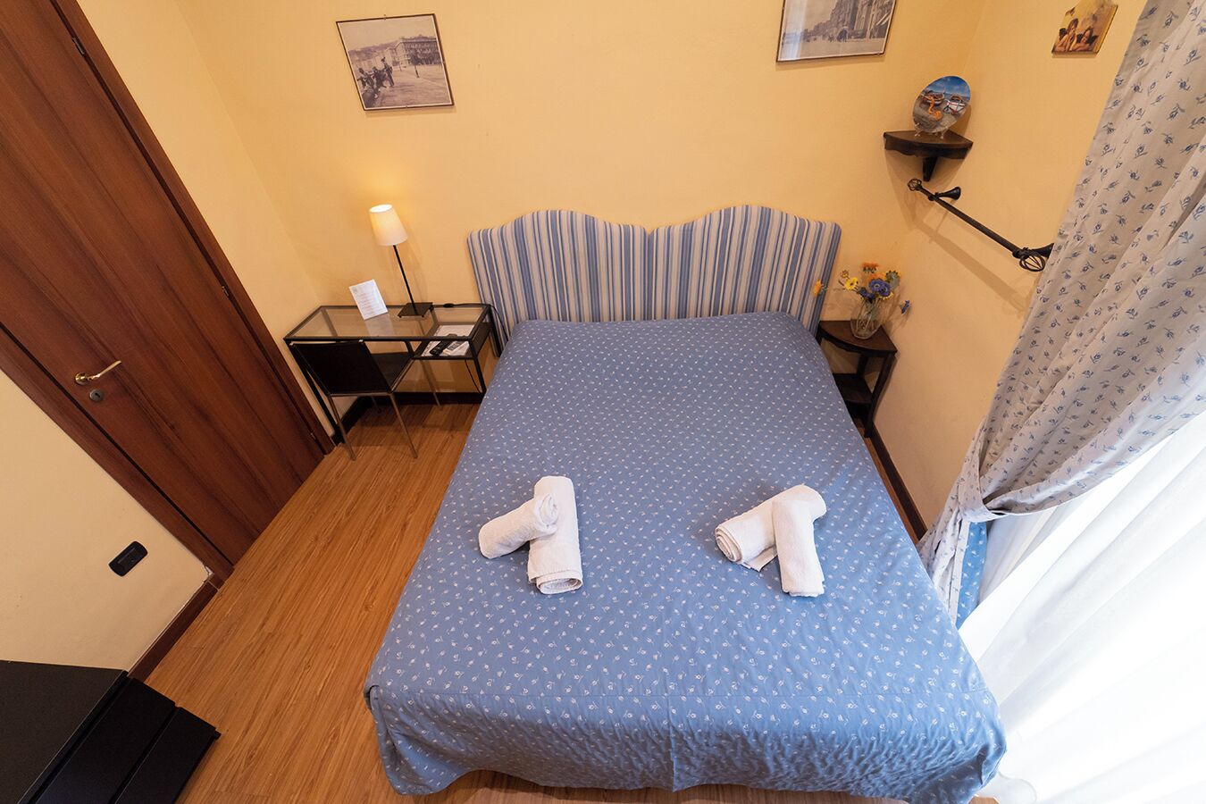 Una camera d'albergo con un letto, una scrivania, una sedia e una lampada.