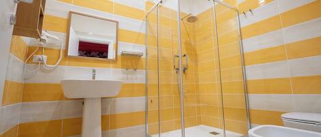 Een badkamer met een glazen douchecabine, een wastafel en een toilet.