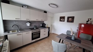 A compact kitchen with a sink, stove, and a dining area with a table and chairs. - Cozy vacation apartment for 2 people - only 15 minutes to Boltenhagen (Upahl)