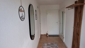 A hallway with a patterned rug, a wooden door, and a mirror on the wall. - Cozy vacation apartment for 2 people - only 15 minutes to Boltenhagen (Upahl)