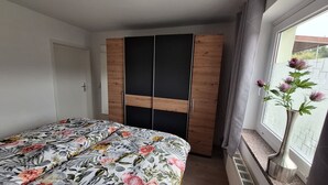 A bedroom with a bed, a wardrobe, and a window with a view. - Cozy vacation apartment for 2 people - only 15 minutes to Boltenhagen (Upahl)