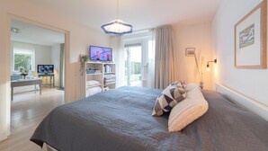 Un dormitorio con una cama grande, televisión y un escritorio con computadora.
