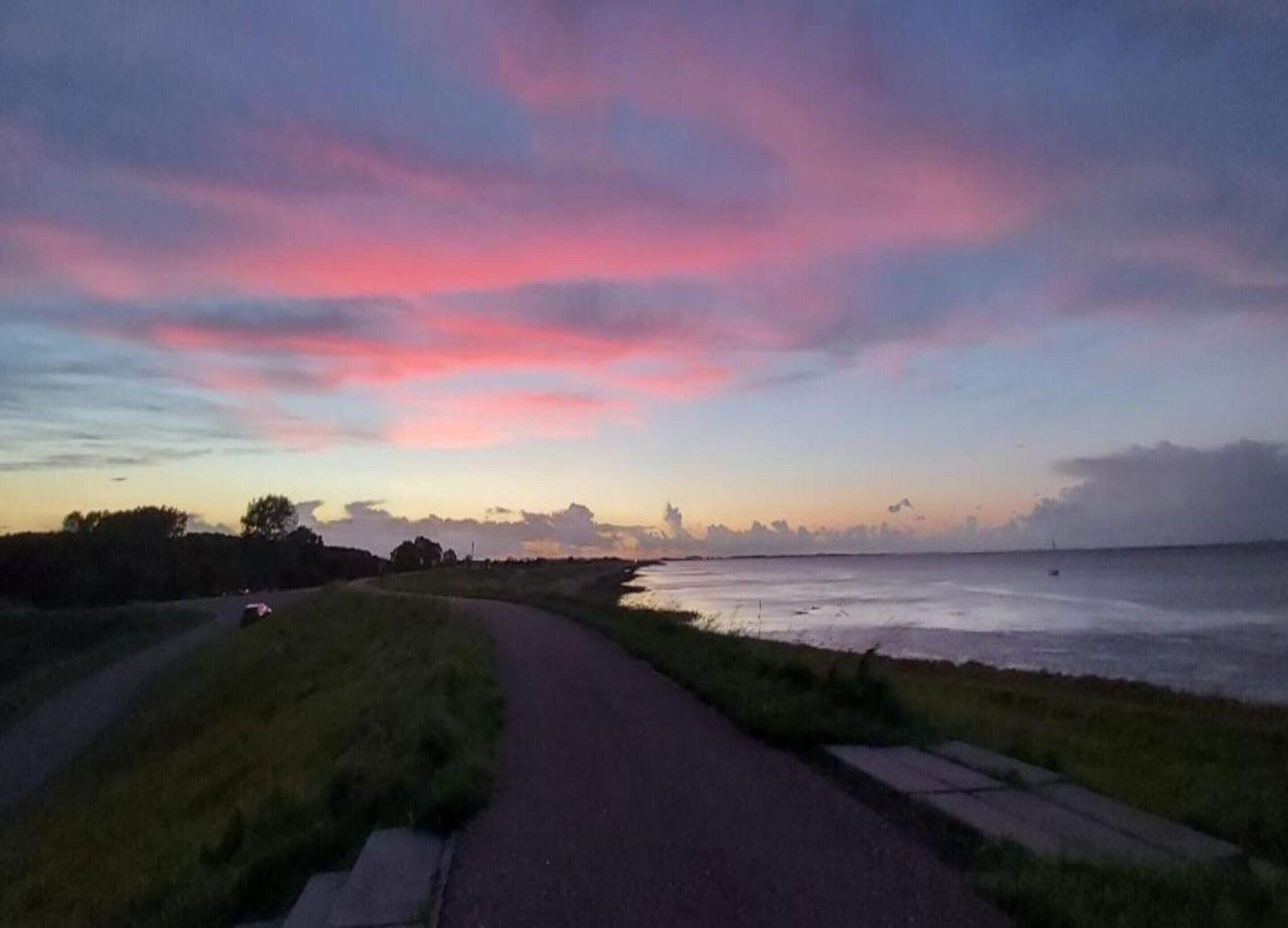A coastal road with a grassy verge and a view of the sea.