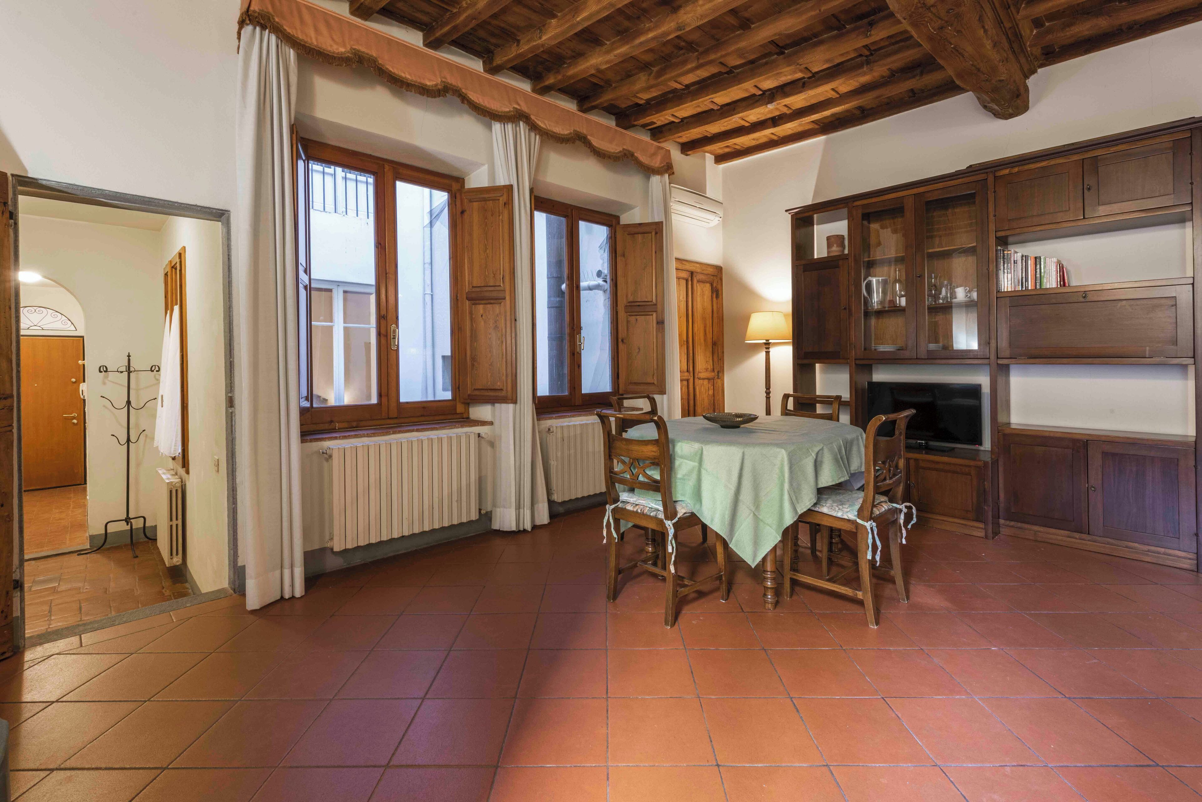 A dining area with a table and chairs, wooden cabinets, and a radiator.