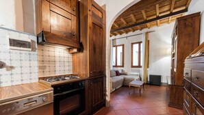 A kitchen with wooden cabinets, a stove, and a tiled backsplash. - Borgo Allegri Palace by MMega (Florence)