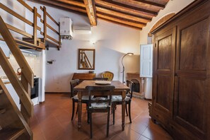 Un comedor con una mesa y sillas de madera, una escalera y un gran armario de madera.