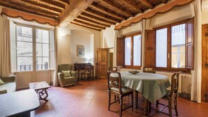A dining area with a table set for four, wooden chairs, and a wooden cabinet. - Borgo Allegri Palace by MMega (Florence)