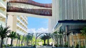 Una plaza urbana moderna con una estructura de cubierta de vidrio, palmeras y edificios contemporáneos.
