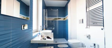 A modern bathroom with a large mirror, a sink, a toilet, and a bidet.