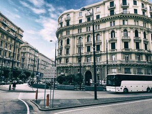A historic building with classical architecture, a bus stop, and a clear sky. - H.R. BOUTIQUE PORTO NAPOLI CENTRO by ClaPa Group Dislocated Hospitality (Naples)