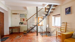 A spacious living area with a staircase leading to an upper floor, a dining table, and a sofa.