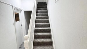 Un pasillo estrecho con una escalera alfombrada que lleva a una puerta.